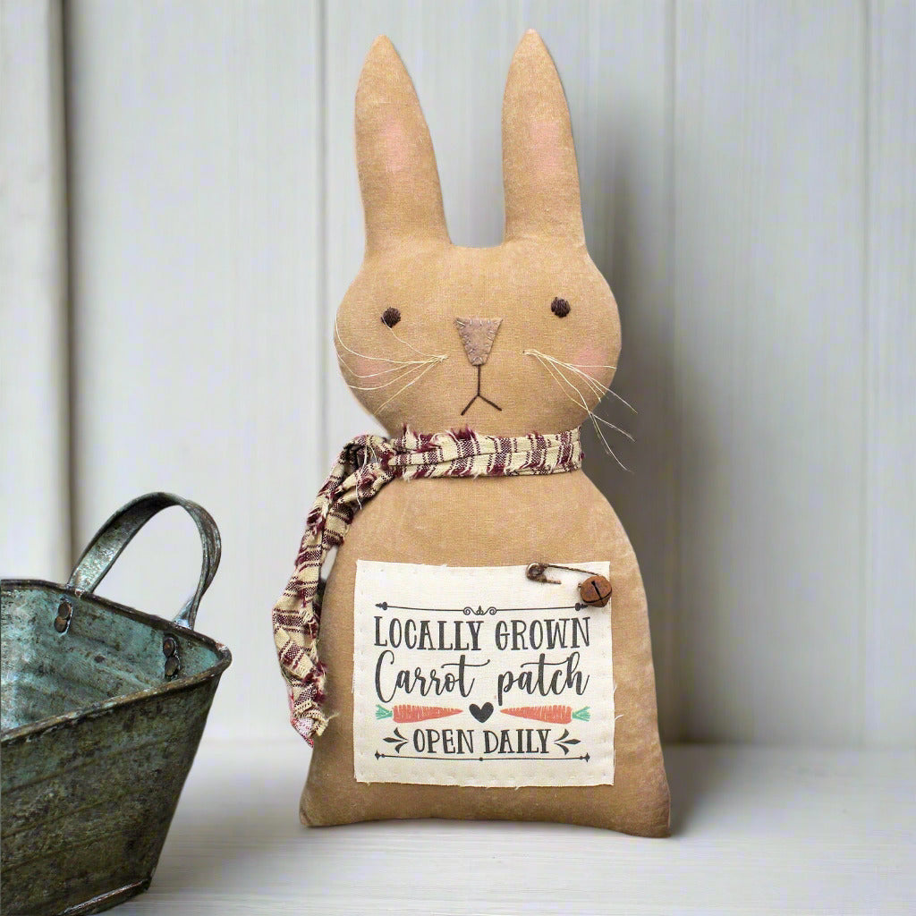 Fabric rabbit with a sign on a wooden background