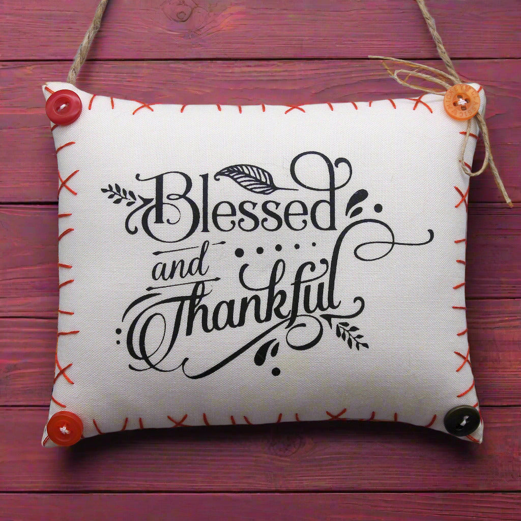 Decorative pillow sign with 'Blessed and Thankful' text on a wooden background