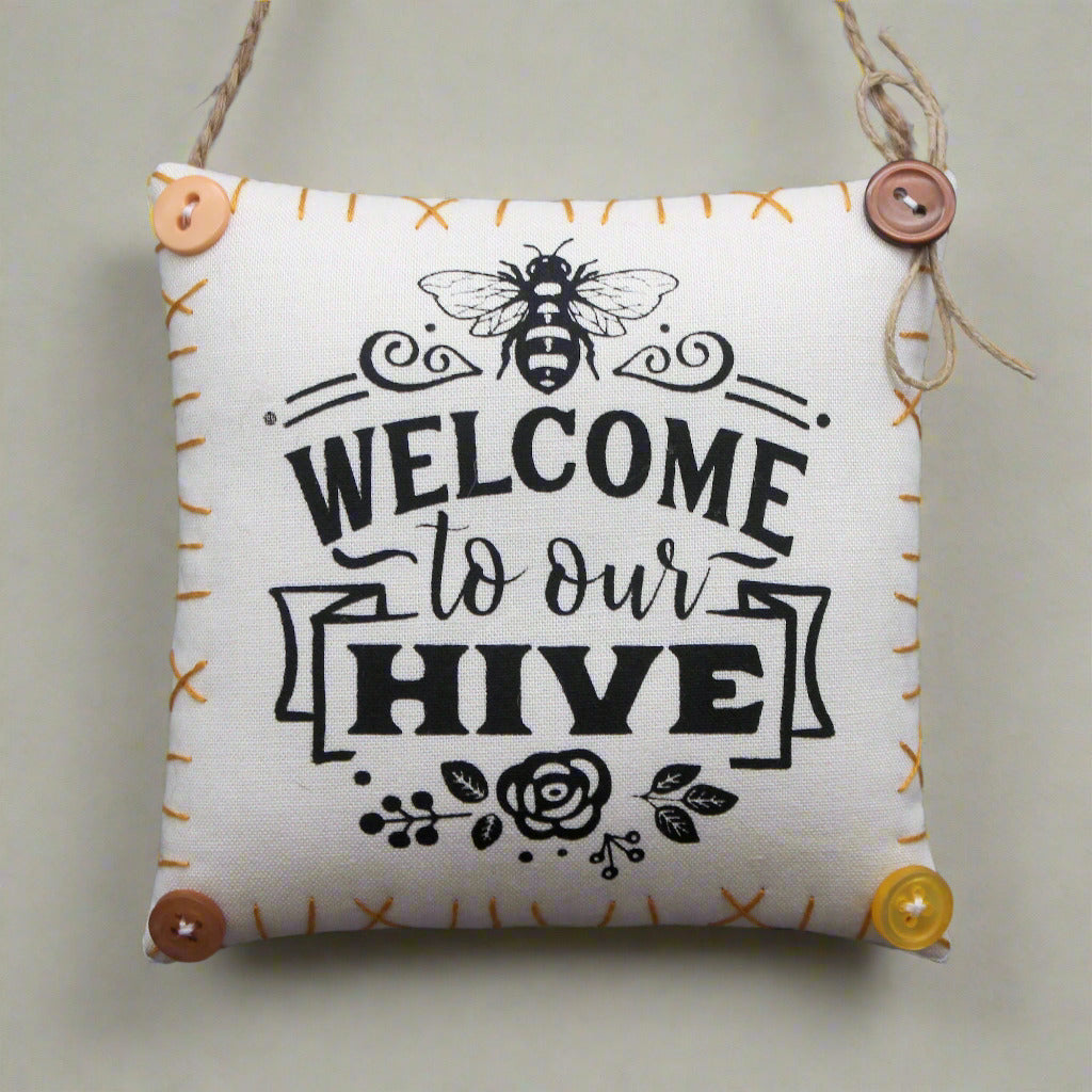 Decorative pillow with 'Welcome to our Hive' text and bee design