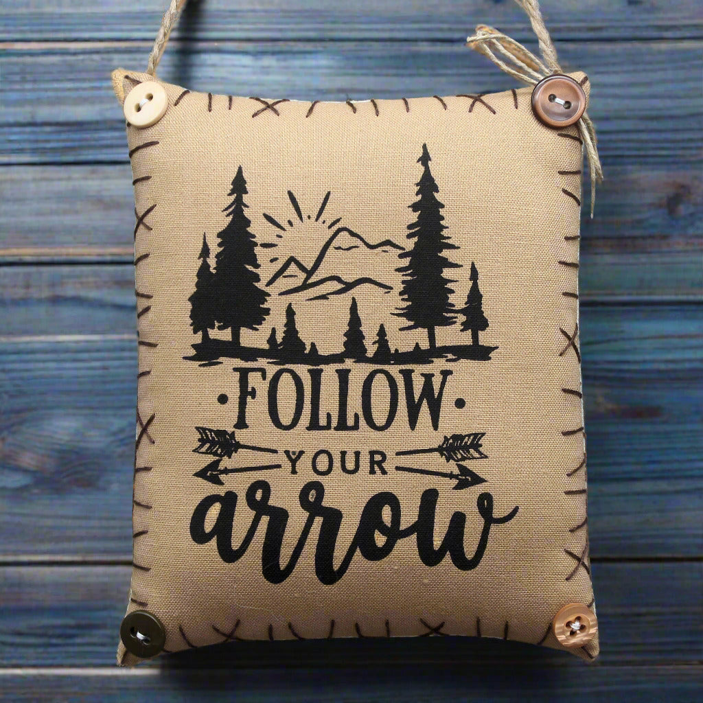 Hanging mini pillow sign with 'Follow Your Arrow' text and nature design