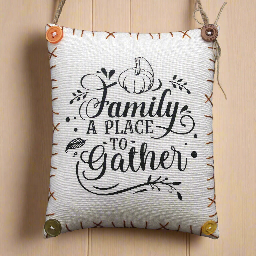 Fabric pillow sign with 'Family is a place to gather' text