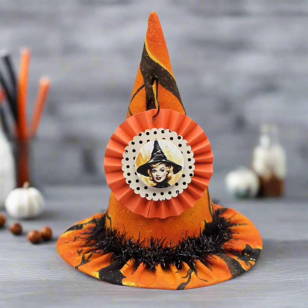 Halloween-themed witch hat with decorative ribbon on a gray background