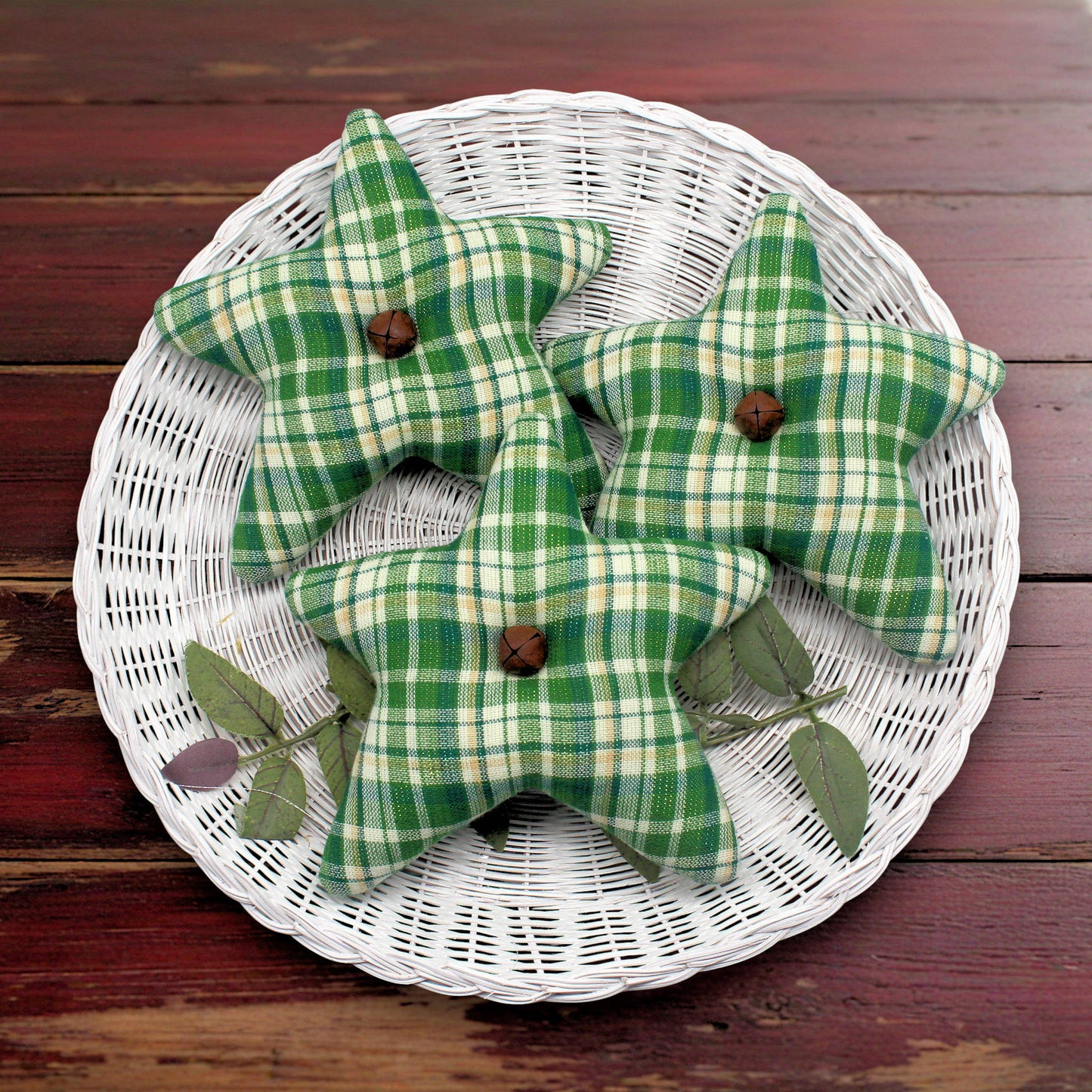 Green plaid star-shaped decorative items on a white woven basket against a wooden background