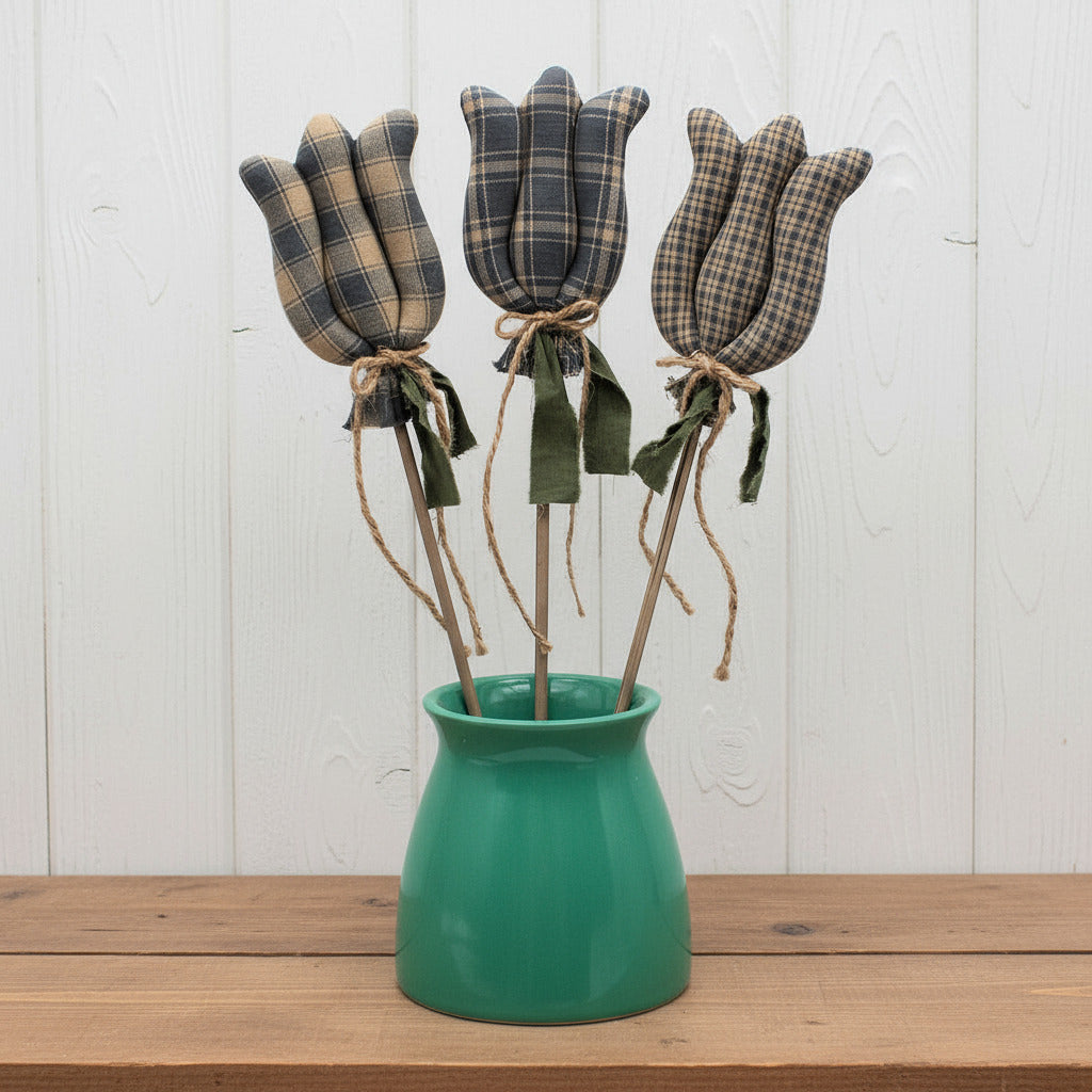 Three colonial blue fabric tulips in a green vase on a white background