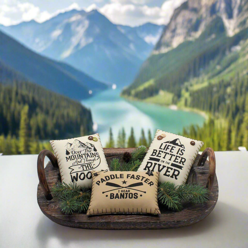 Three decorative pillows with text in a wooden tray