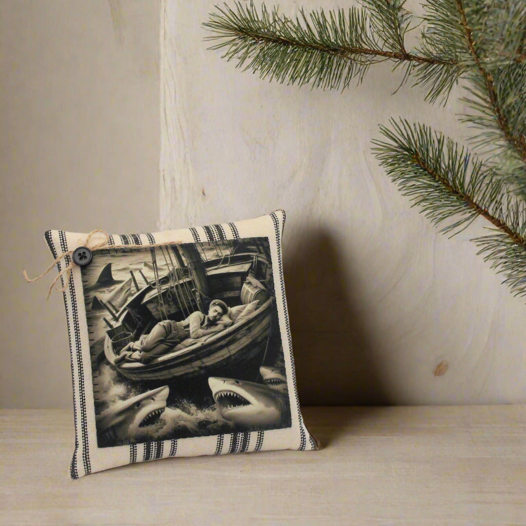 Decorative pillow with a black and white design of a person in a boat surrounded by sharks