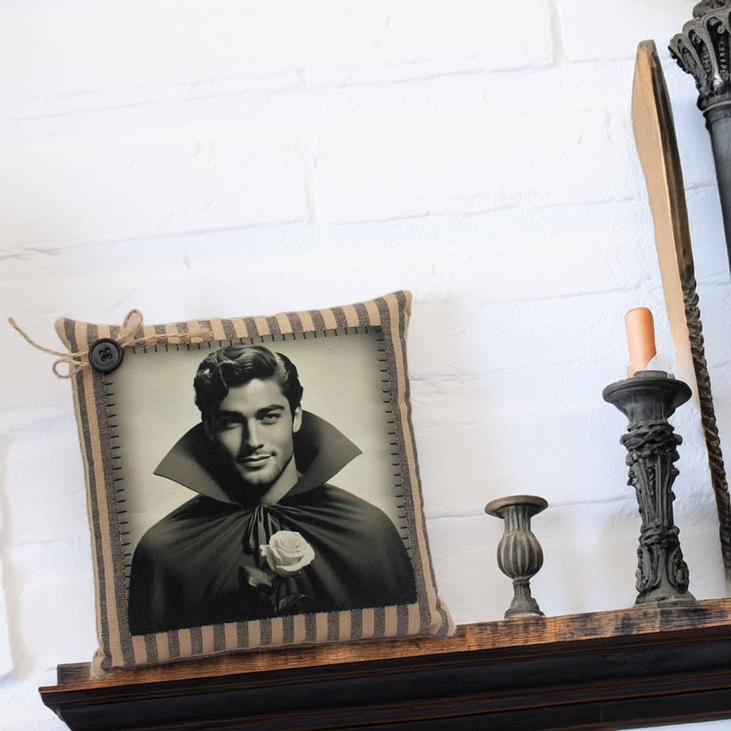 Decorative pillow with a portrait of a handsome young vampire in a cape on a shelf with candles.