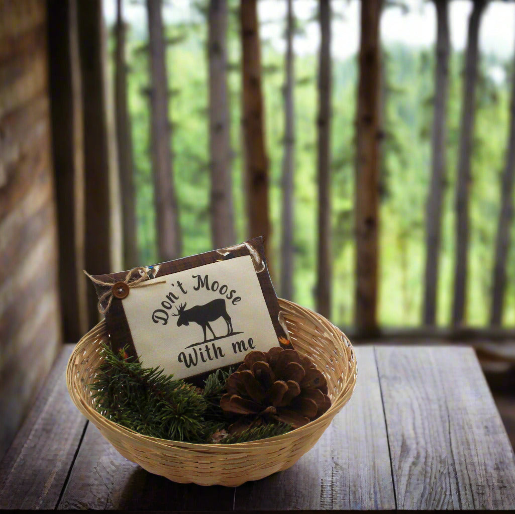 Decorative basket with a sign and pinecones on a wooden surface with a forest background