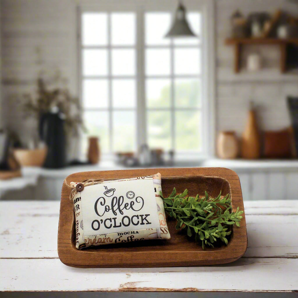 Wooden tray with a decorative sign reading 'Coffee O'Clock' on a kitchen counter.
