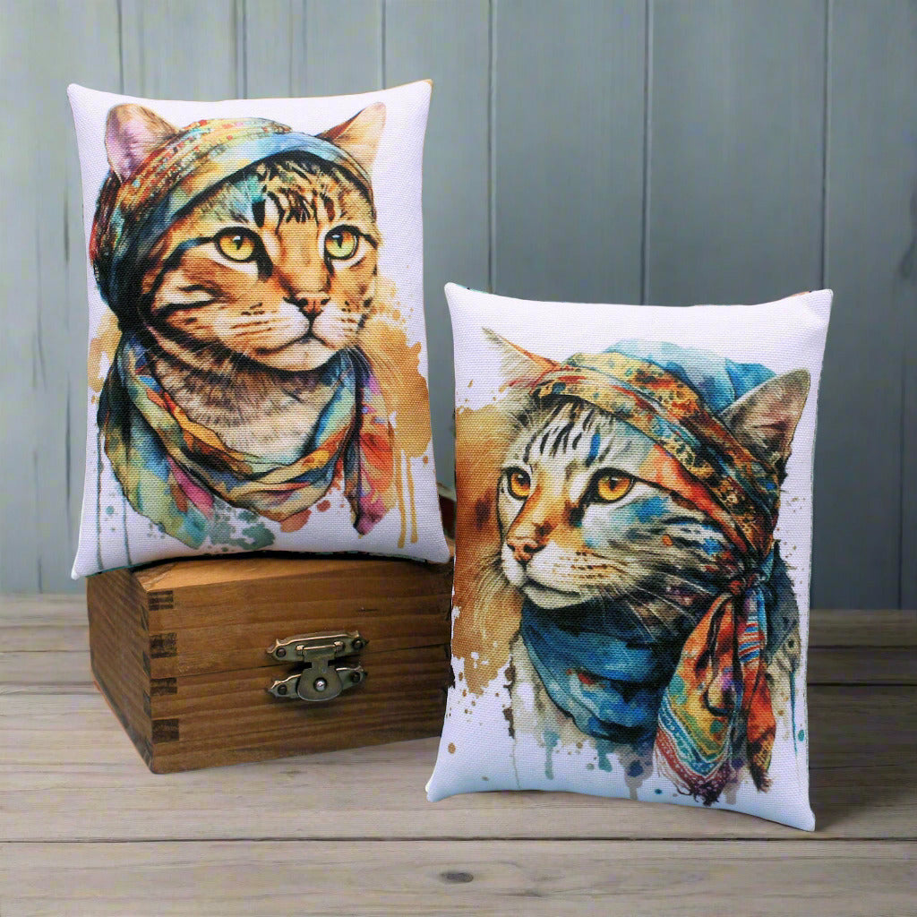 Two pillows with cat designs and colorful headscarves on a wooden box and blue surface.
