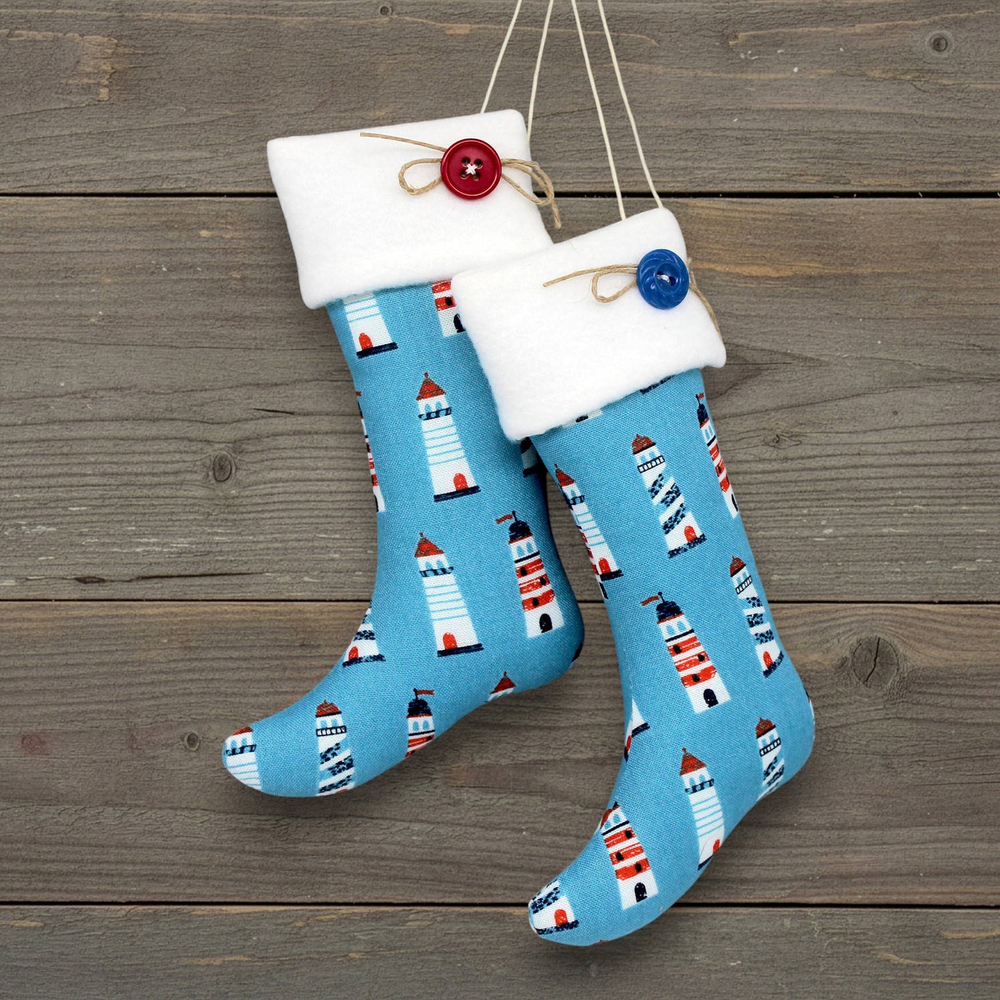 Pair of nautical-themed handmade Christmas tree stocking ornaments with lighthouse designs.