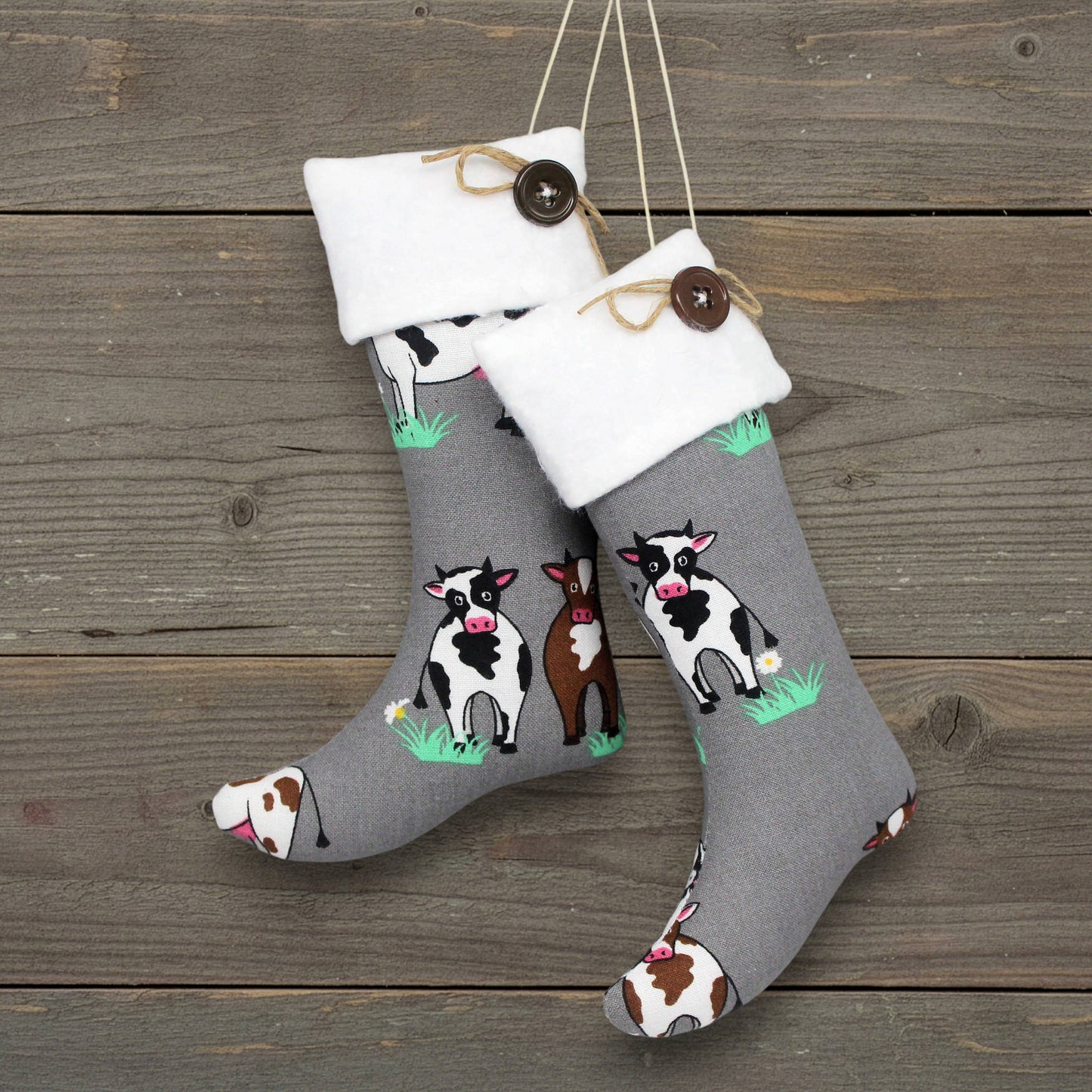 Gray Christmas handmade stocking ornaments with cow designs on a wooden surface