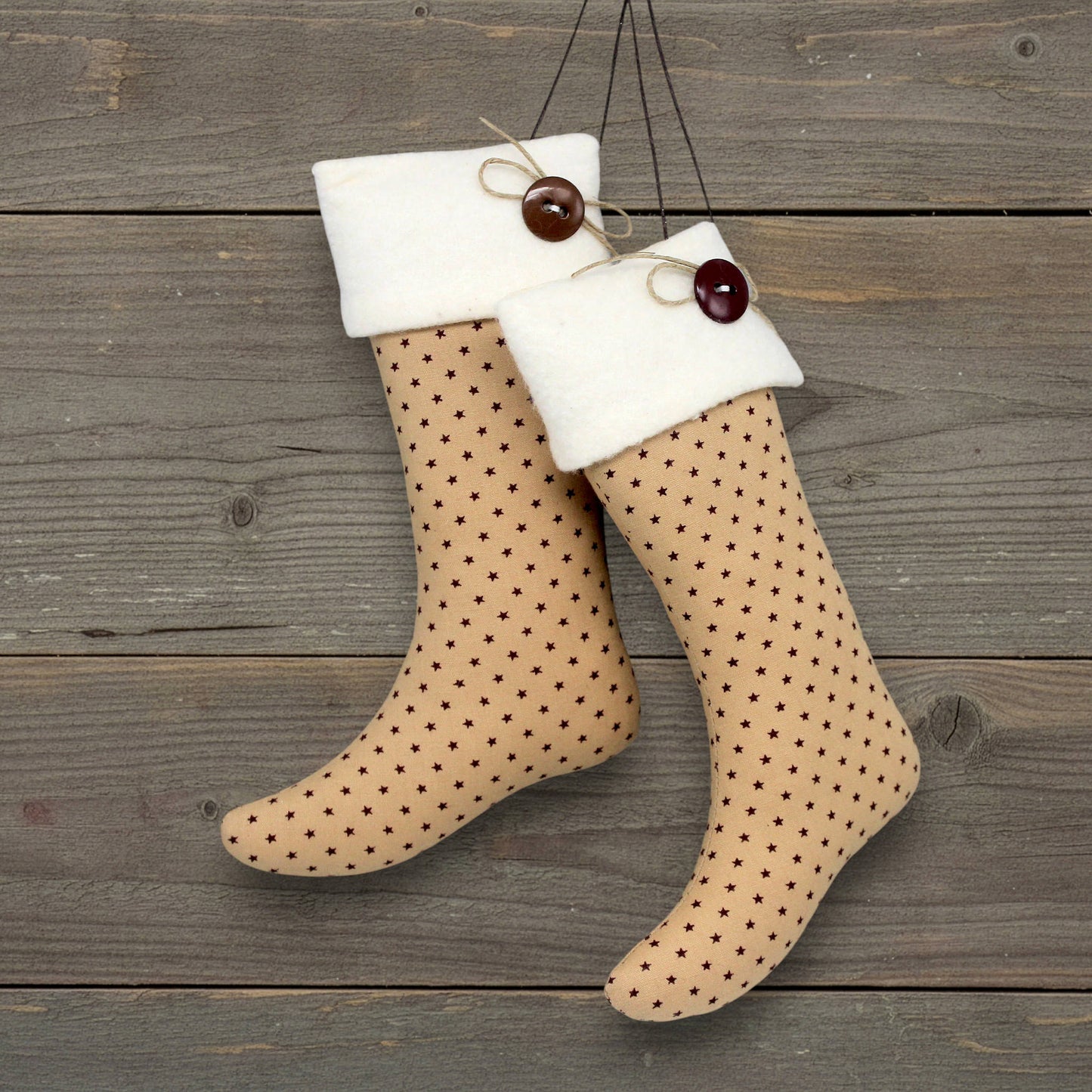 Pair of handmade primitive Christmas stocking ornaments with tiny burgundy stars on a tan background