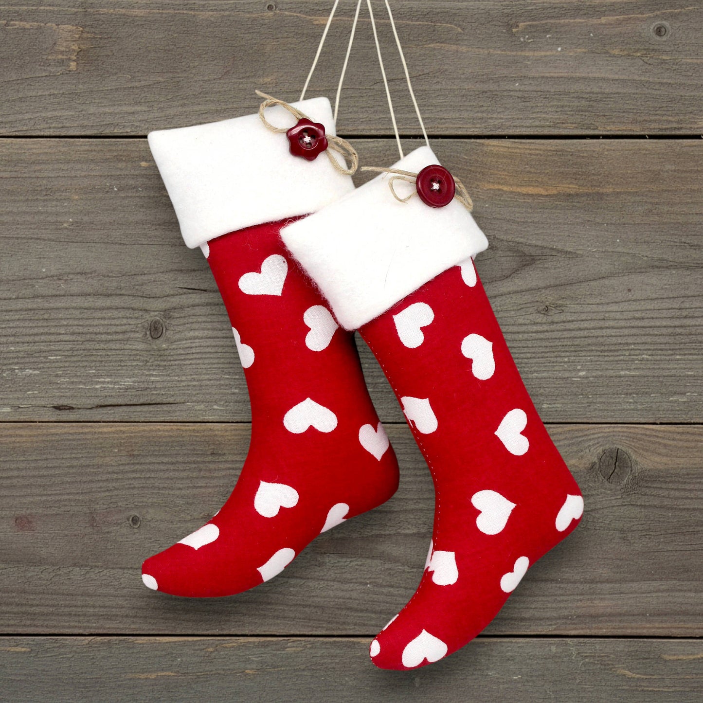 Pair of handmade Christmas stocking ornaments with white hearts on a red background