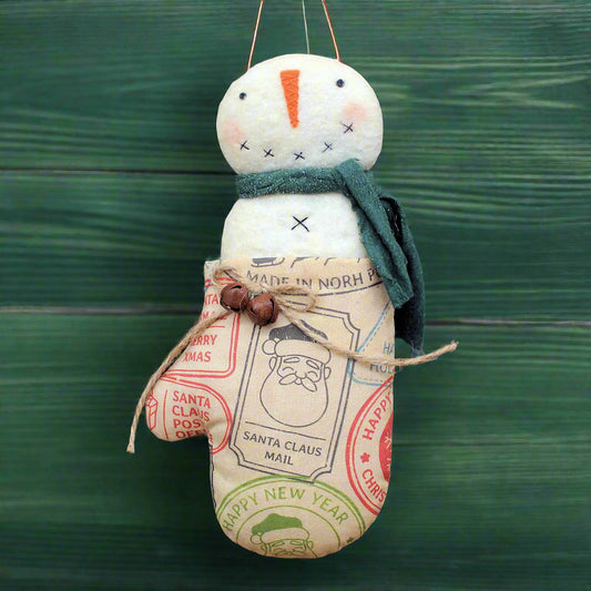 Handmade snowman ornament with vintage-style labels on a green background