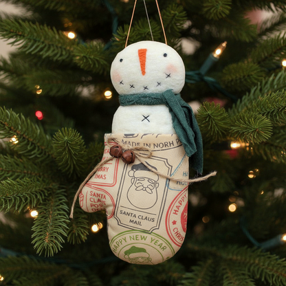 Decorative snowman ornament with a vintage-style label hanging on a Christmas tree.