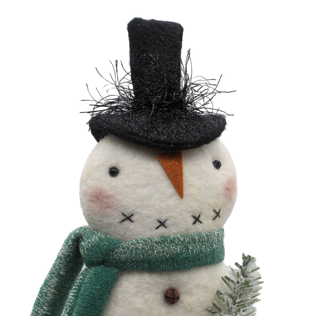 Handmade snowman figurine with a black top hat, green scarf, and pine on a white background
