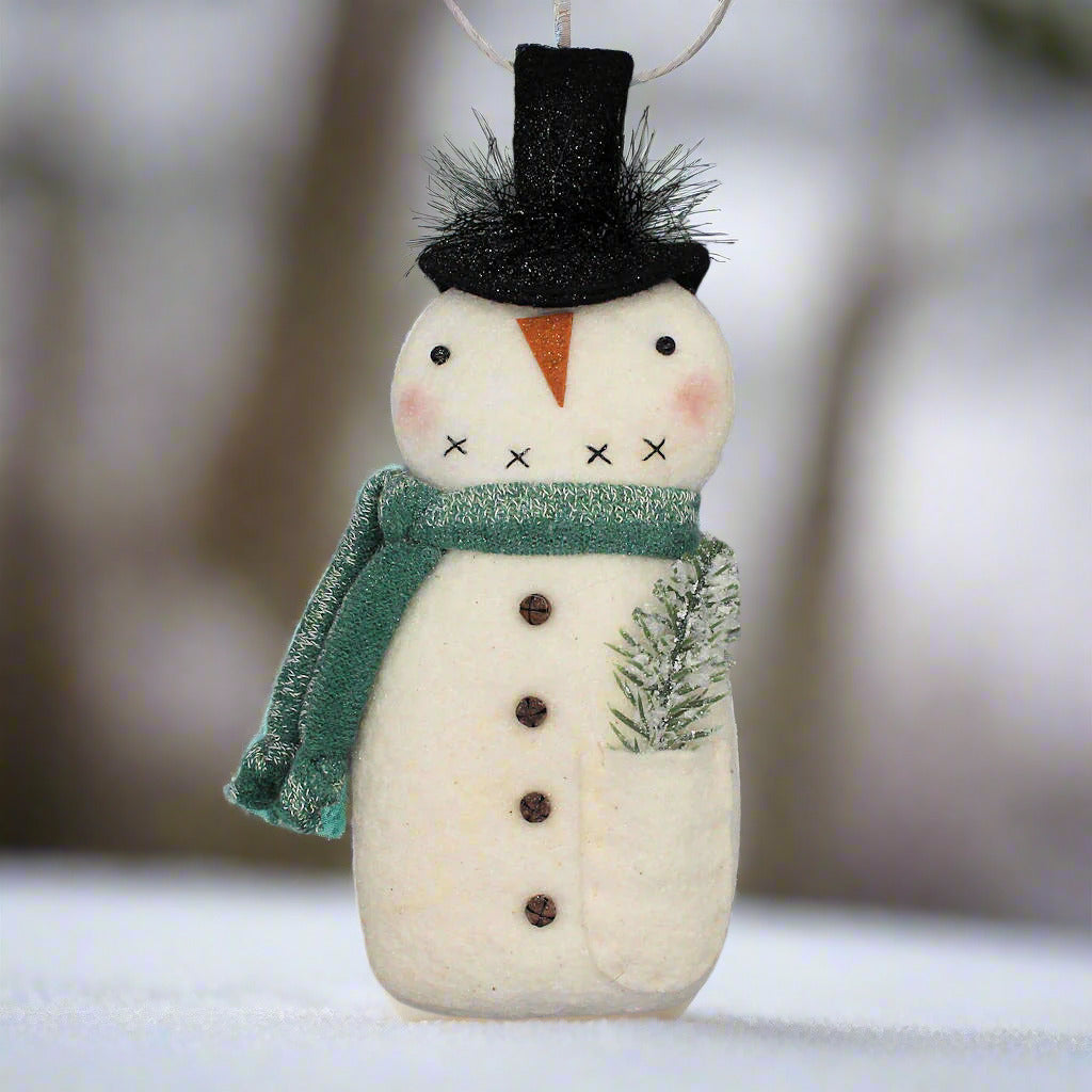 Decorative primitive snowman ornament with a green scarf on a gray background