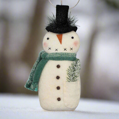 Decorative primitive snowman ornament with a green scarf on a gray background