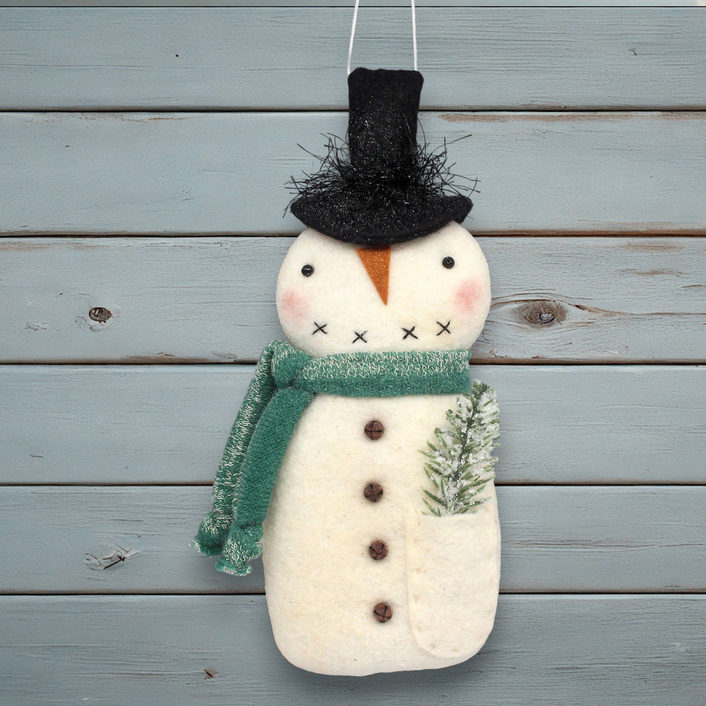 Decorative snowman ornament with a green scarf and black top hat on a wooden background