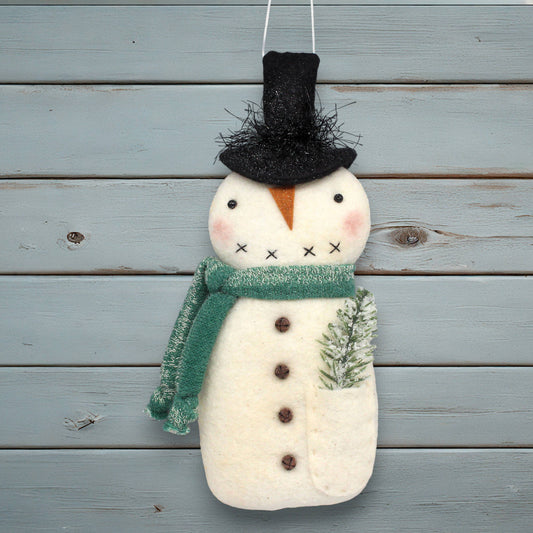 Decorative snowman ornament with a green scarf and black top hat on a wooden background