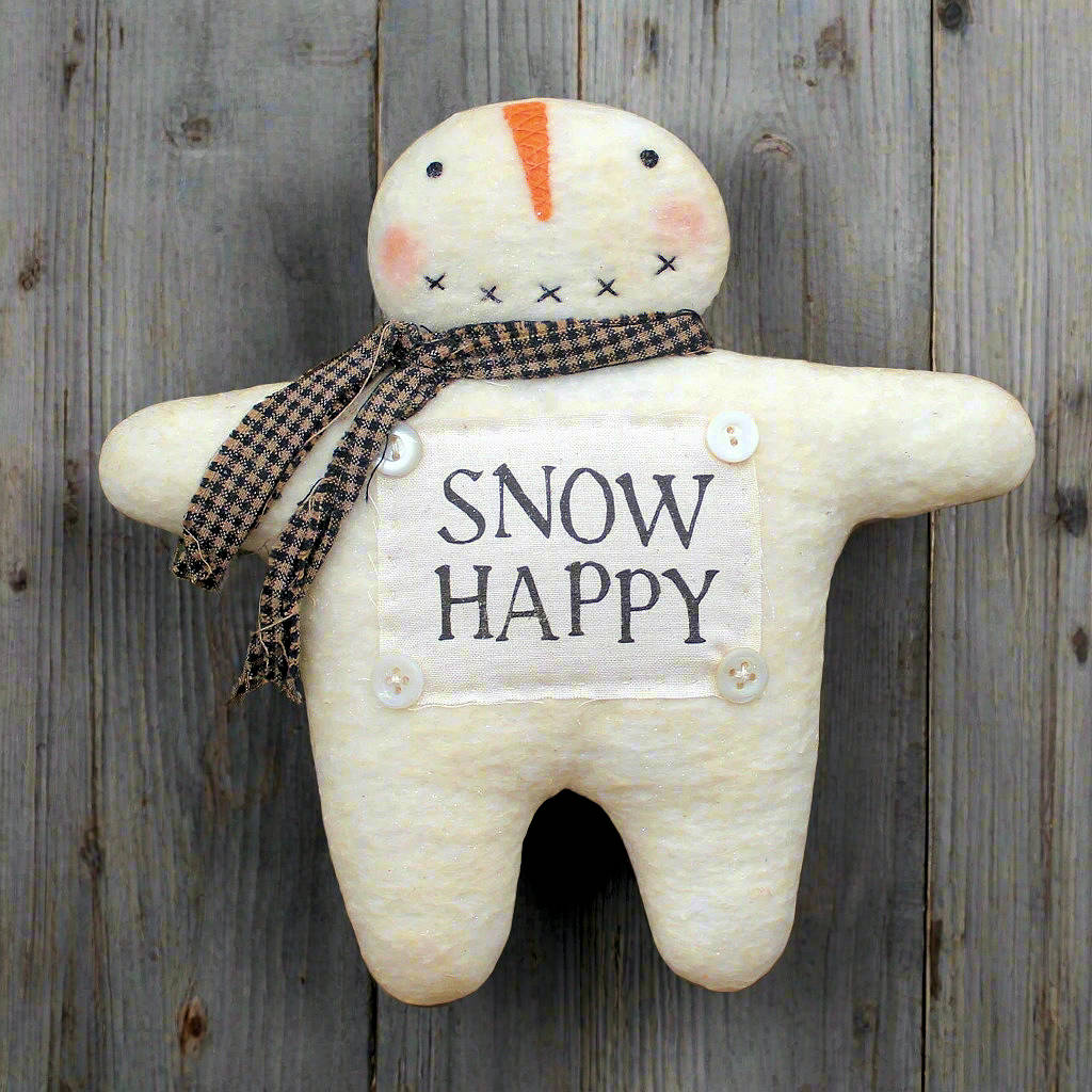 Snowman-shaped plush toy with 'SNOW HAPPY' sign against a wooden background
