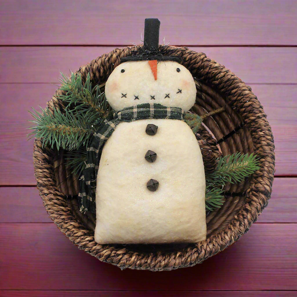 Primitive snowman figure in a woven basket with greenery