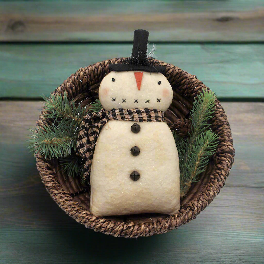 Decorative primitive snowman ornament with a plaid scarf in a woven basket