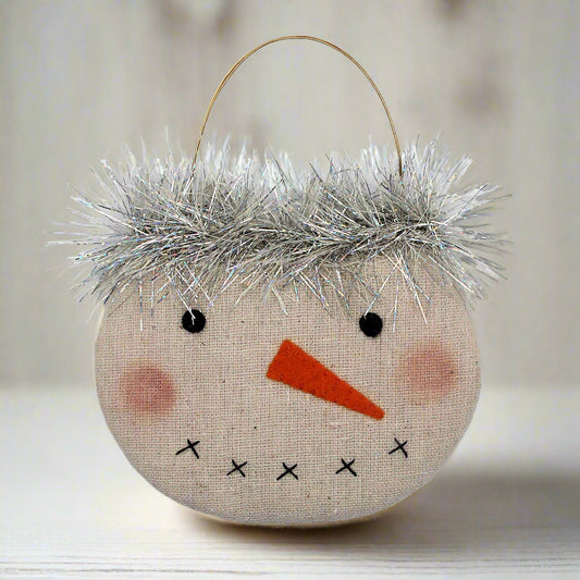 Decorative snowman face ornament with tinsel hair on a white background