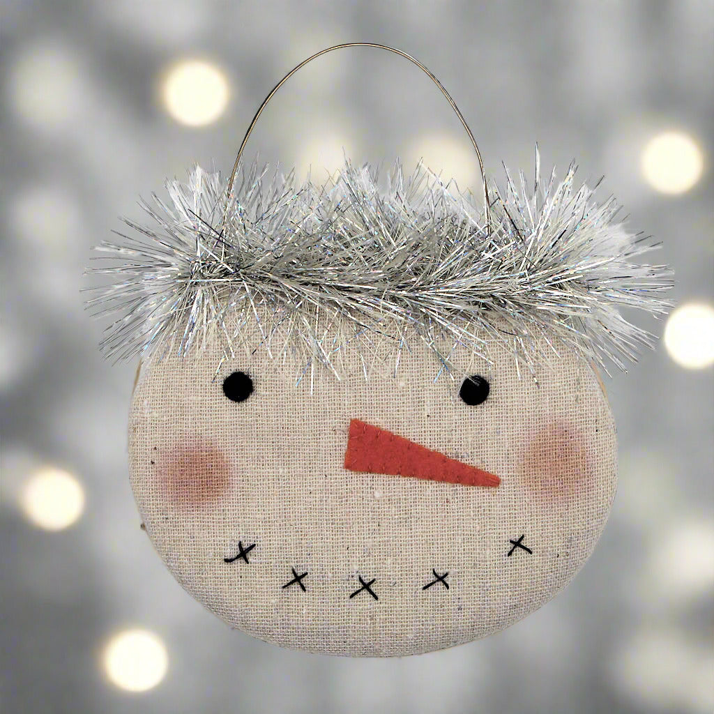 Decorative snowman ornament with tinsel hair on a white background