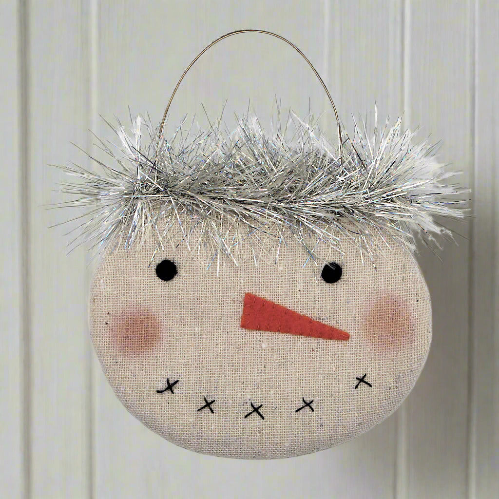 Decorative snowman ornament with tinsel hair on a white background