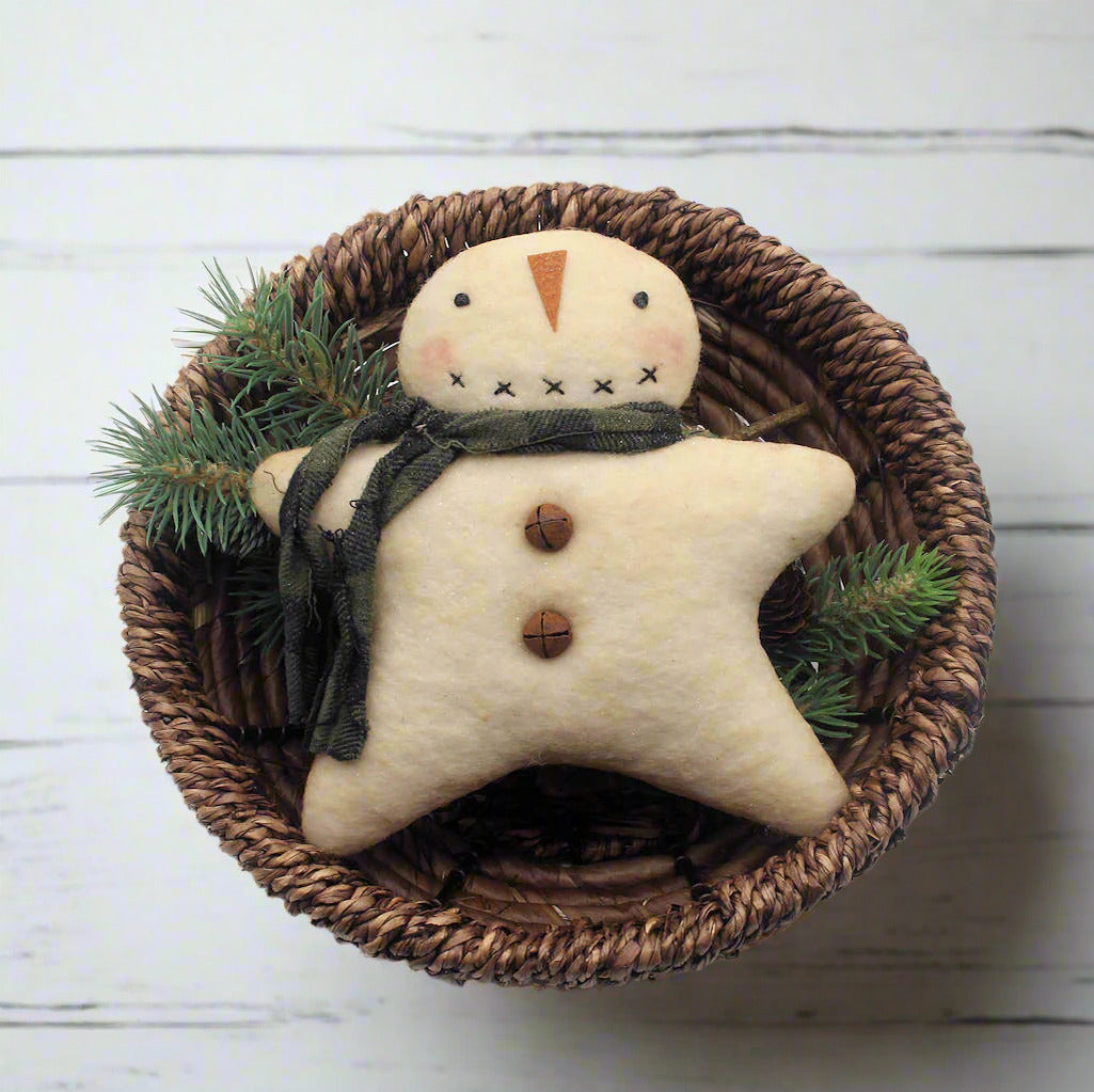 Star-shaped snowman ornament with a green scarf in a woven basket on a white background