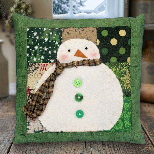 Decorative pillow with a snowman design on a wooden surface