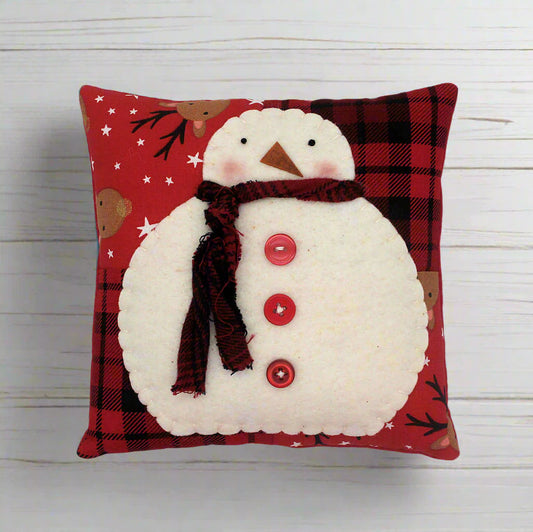 Decorative pillow with a snowman design on a red plaid background