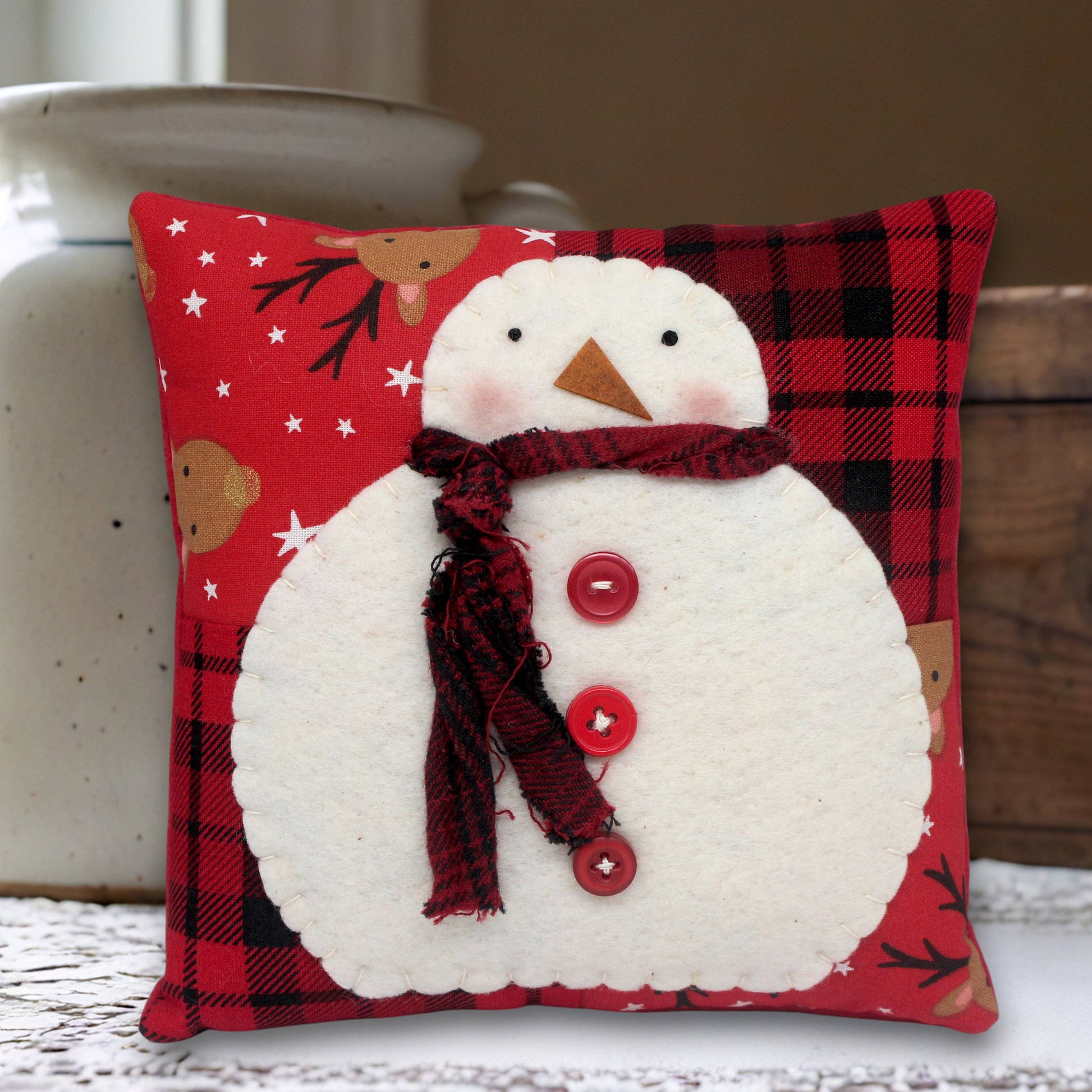 Decorative pillow with a snowman design on a red plaid background
