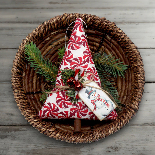 Decorative Christmas tree ornament with red and white pattern on a woven plate with greenery.