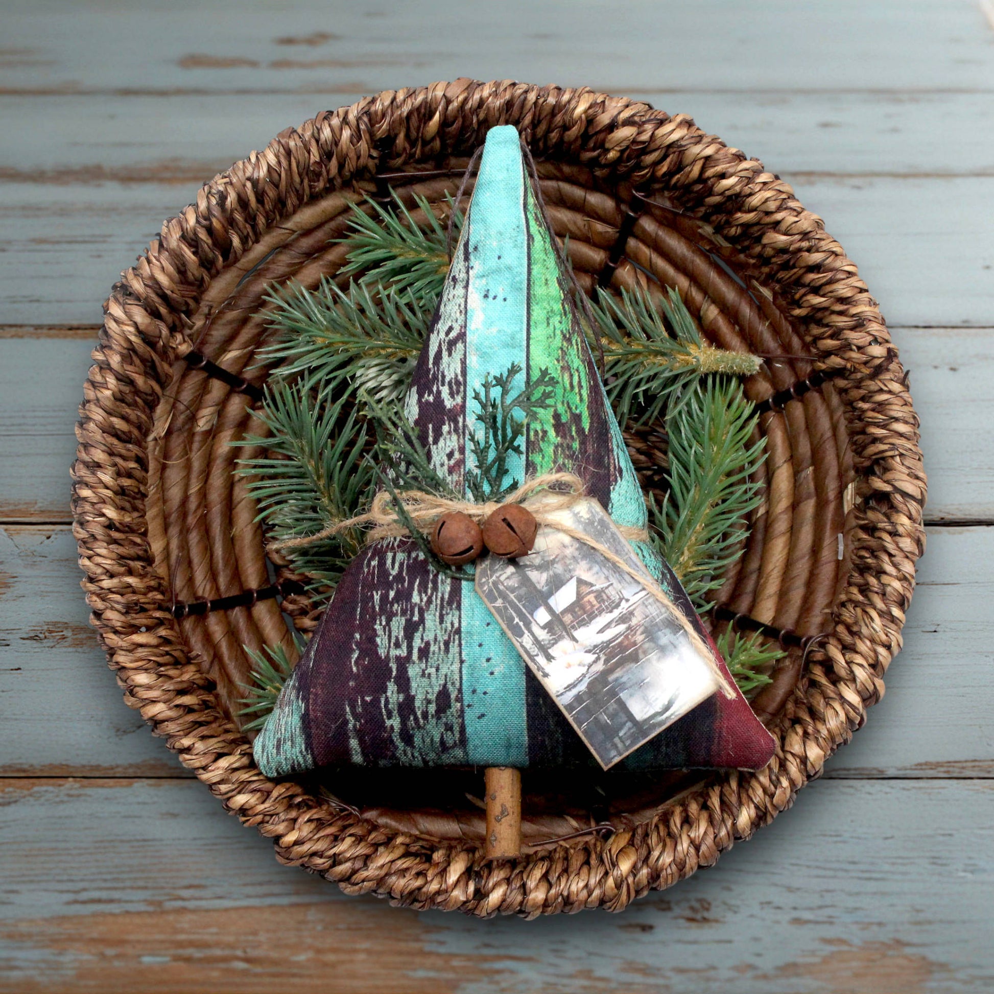 Decorative Christmas tree ornament with green and purple colors on a woven basket with pine branches.