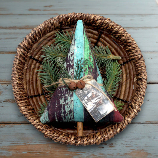 Decorative Christmas tree ornament with green and purple colors on a woven basket with pine branches.