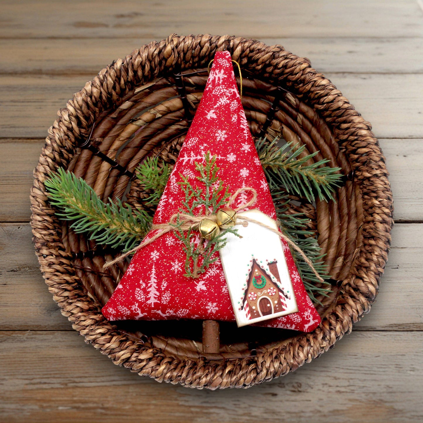 Decorative Christmas tree with red fabric and white snowflake patterns on a woven basket with greenery