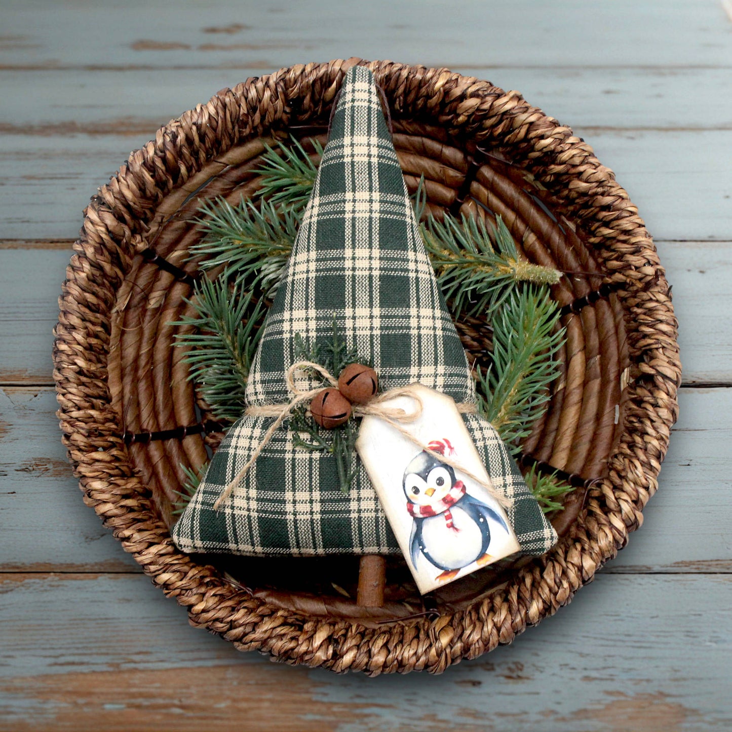 Decorative green plaid tree with a penguin tag on a woven plate.