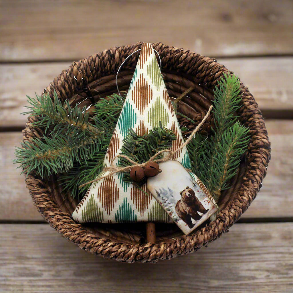 Tree-shaped Christmas ornament or bowl filler sewn from woodsy print fabric with rusty bells, greenery and a tag with a grizzly bear