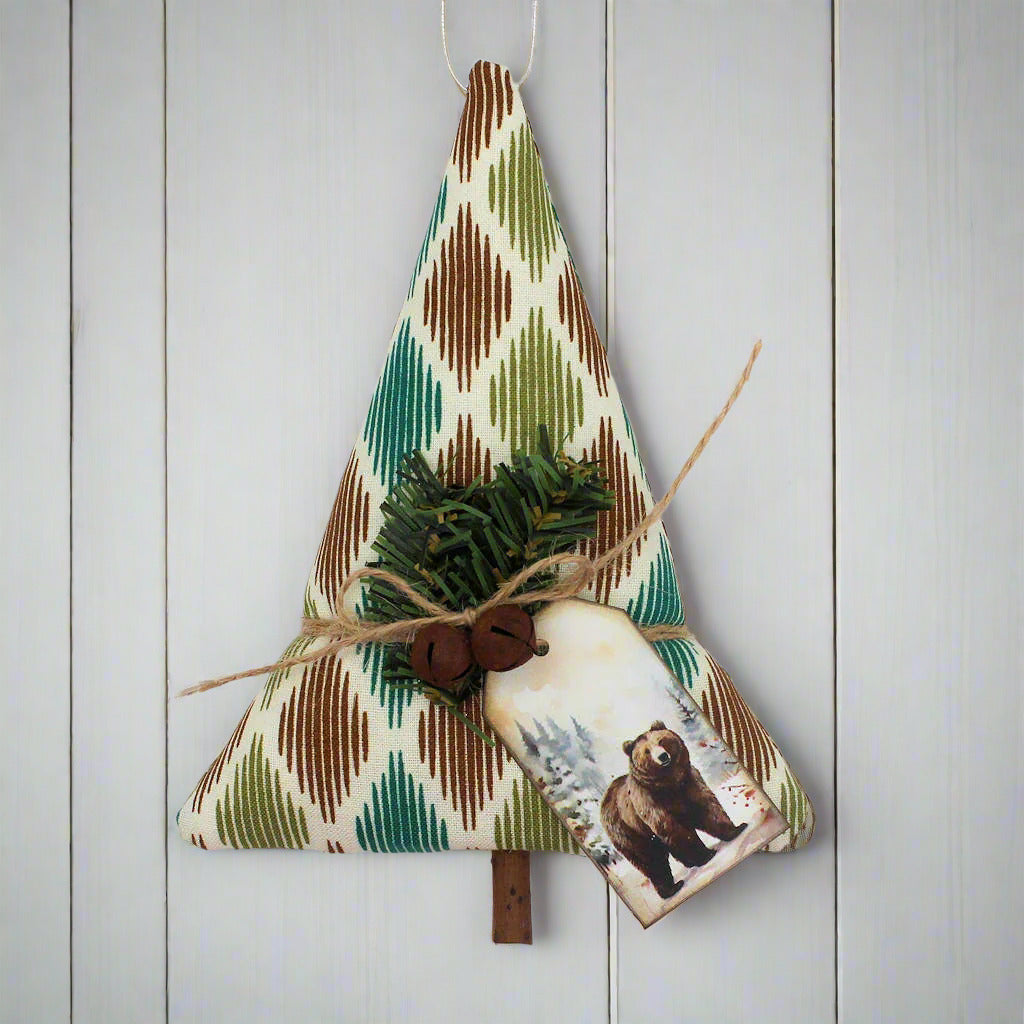Tree-shaped Christmas ornament or bowl filler sewn from woodsy fabric with rusty bells, greenery and a tag with a brown bear