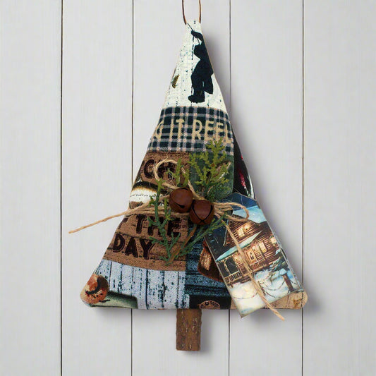 Tree-shaped ornament sewn from cotton print fabric with a fishing cabin design, with rusty bells, greenery and a tag