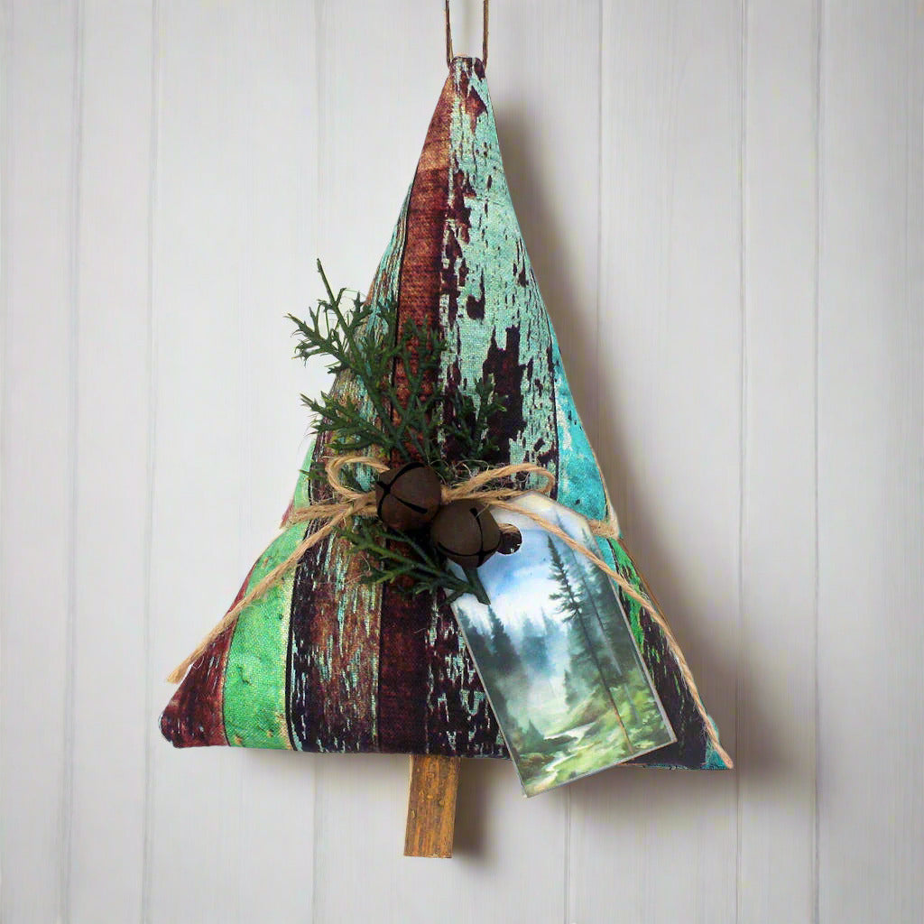 Tree-shaped Christmas ornament or bowl filler sewn from a fabric with a weathered wood design along with rusty bells, greenery and a tag