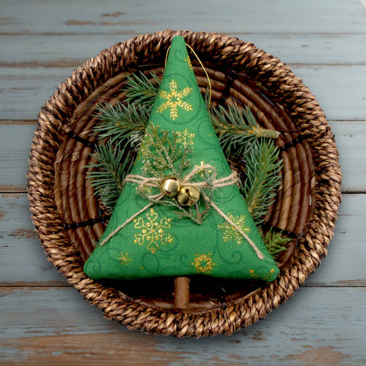 Green fabric Christmas tree ornament with gold details on a woven plate.