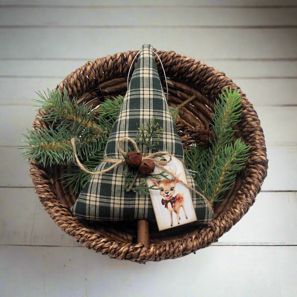 Decorative Christmas tree ornament with plaid pattern and reindeer design in a woven basket with greenery.
