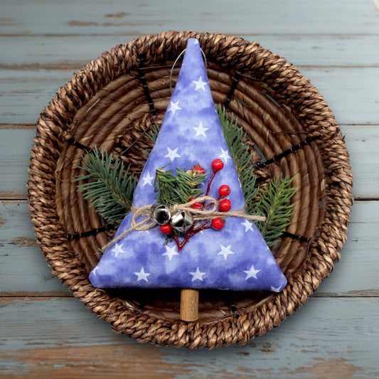 Decorative Christmas tree ornament with blue fabric, white stars, and red berries on a woven plate.