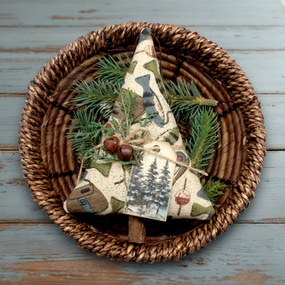 Decorative item with tree design and greenery in a woven basket on a wooden surface