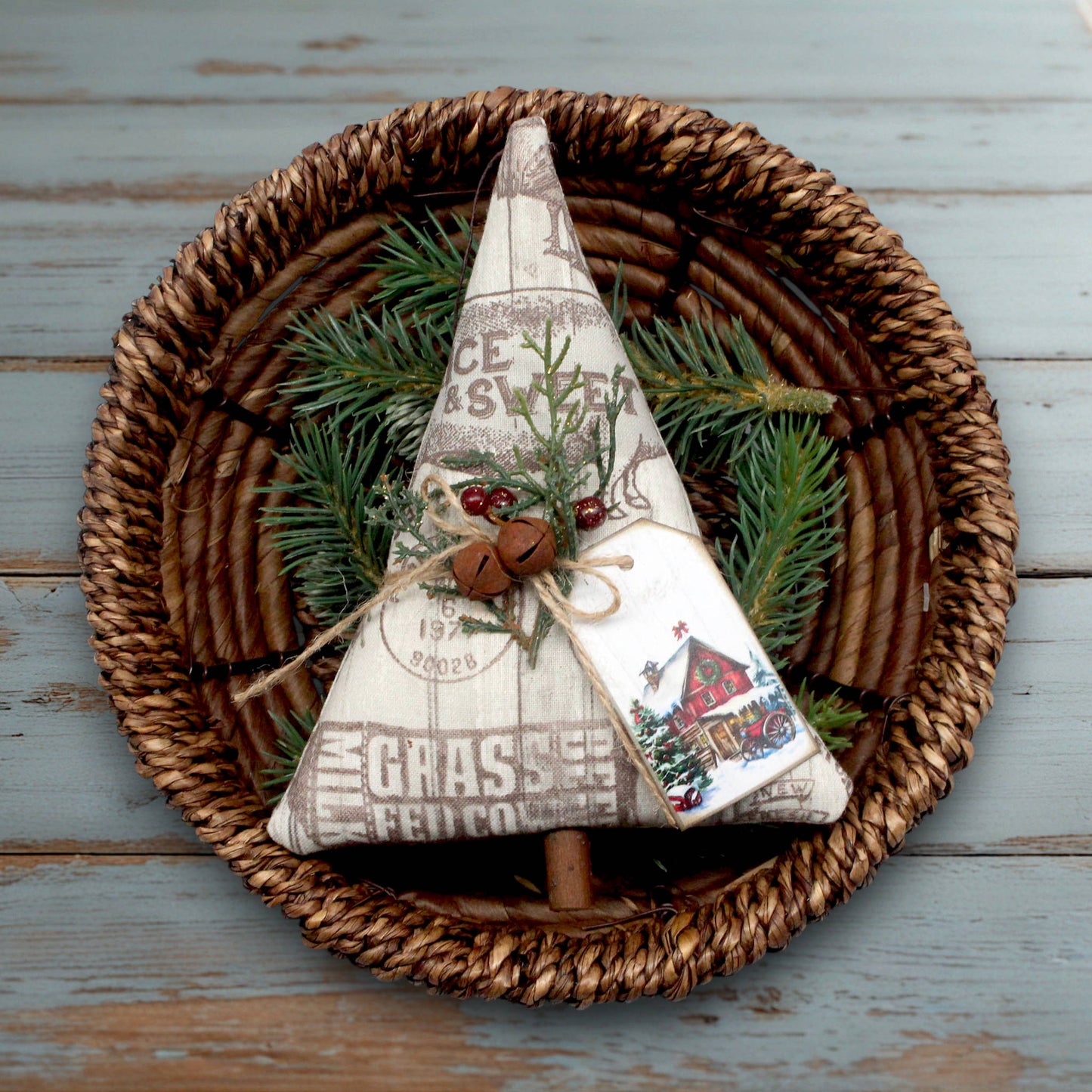 Decorative Christmas tree made of fabric and pine branches on a woven basket with a wooden surface background.