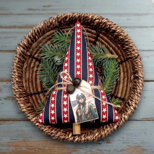 Decorative Christmas tree-shaped ornament with American flag pattern on a woven plate with greenery